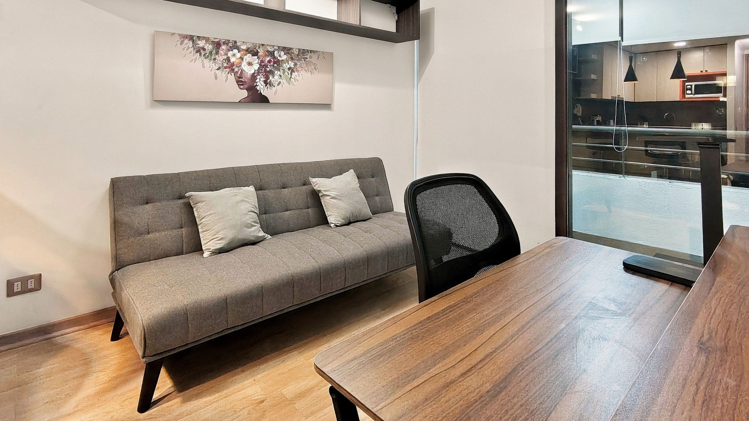 Una sala moderna con un sofá gris, una silla negra y una mesa de comedor de madera.