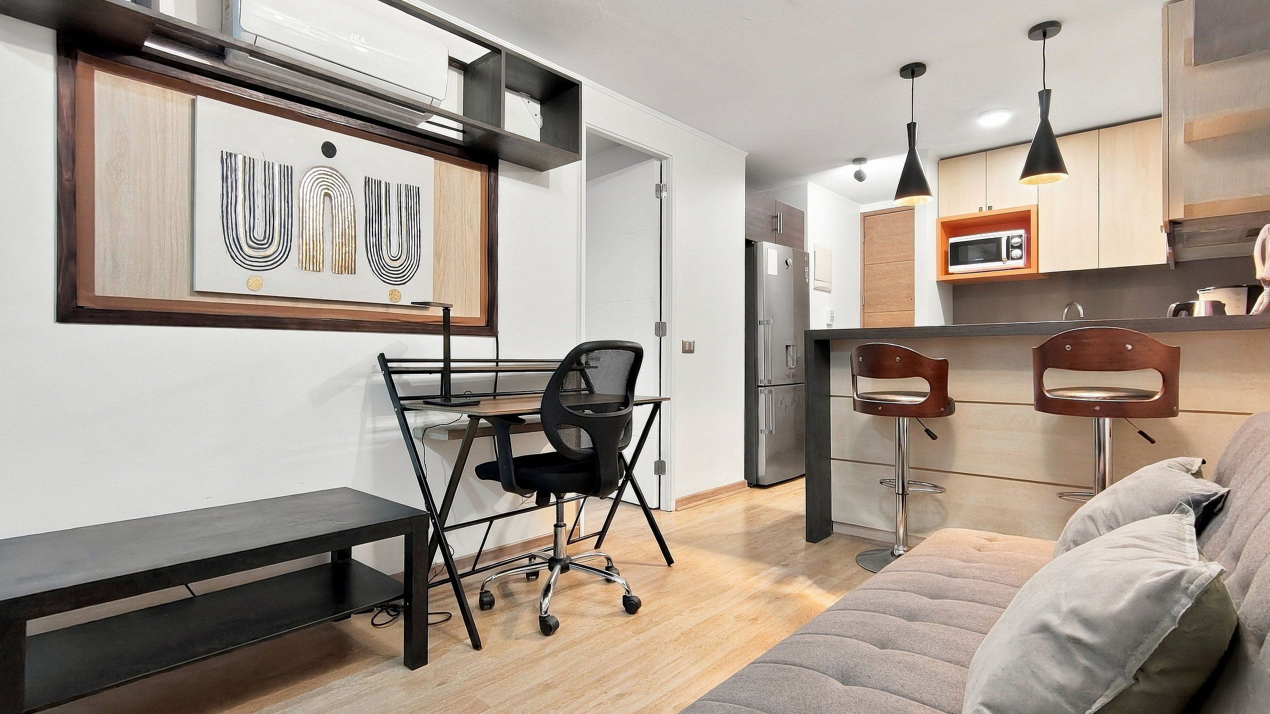 Una cocina moderna con microondas integrado, refrigerador y un armario de madera.
