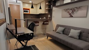Een knus woongedeelte met een kitchenette, een eethoek en een bank.