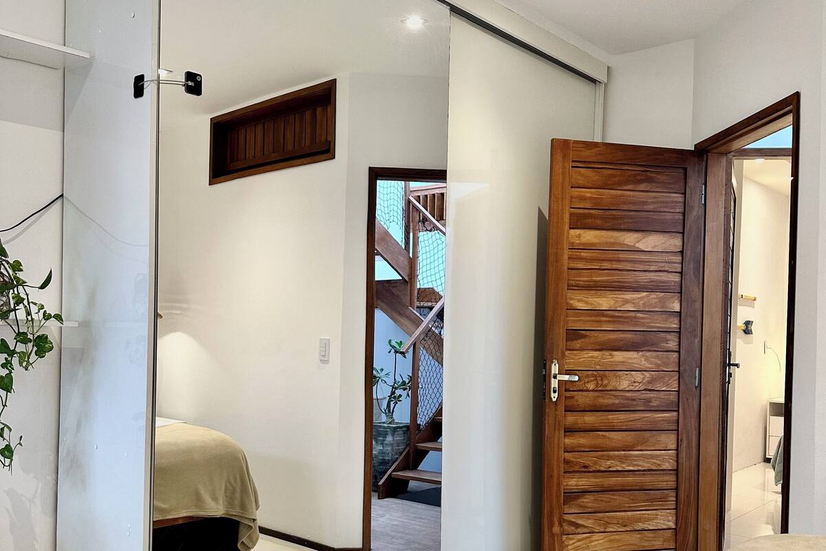 Een moderne hotelkamer met een schuifglasdeur naar een balkon, een houten deur en een opgemaakt bed met opgerolde handdoeken.