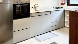 Eine moderne Küche mit Edelstahlgeräten, weißen Schränken und einem eingebauten Backofen.