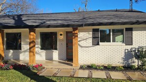 A modern single-story house with a brick exterior, large windows, and a covered porch area.