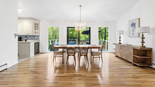 Una cocina amplia con comedor, piso de madera y grandes ventanales con vistas al exterior.