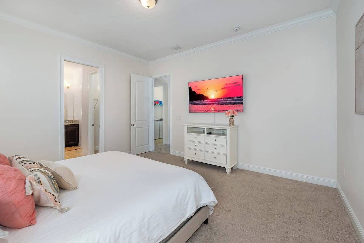 Une chambre à coucher avec un lit, une commode et un tableau représentant un coucher de soleil.