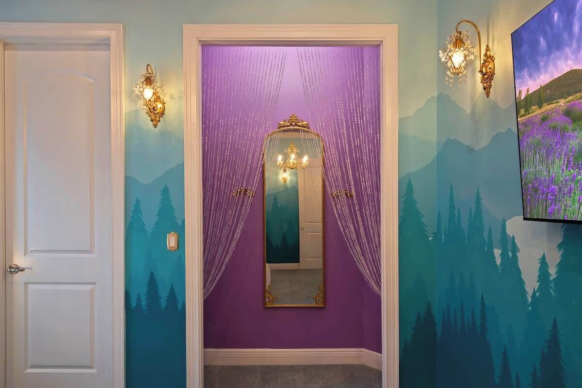 A hallway with a purple wall, a mirror, and a door.