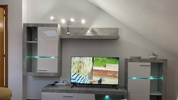 Una sala de estar moderna con un televisor de pantalla plana, estanterías empotradas y un comedor.