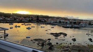Un puerto con barcos y un pueblo al fondo durante el atardecer.