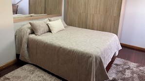 Un dormitorio con cama, un espejo grande y un armario.