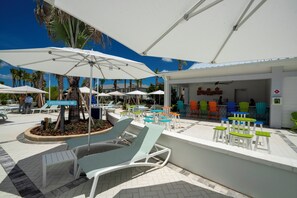 Un espace aménagé au bord de la piscine, avec des chaises longues, des parasols et un restaurant appelé « Rumblers ».
