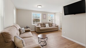 Ein Wohnzimmer mit einer Couch, einem Couchtisch und einem an der Wand montierten Fernseher.