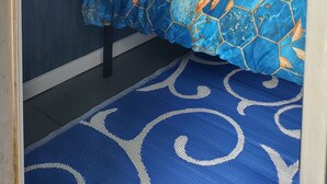 Un dormitorio con cama, una ventana con cortinas, un radiador y un armario pequeño.