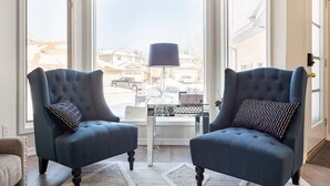 A room with two dark blue armchairs, a small table, and a lamp. - Sunset View House (families) (Calgary)