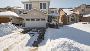 A two-story house with a garage, surrounded by snow. - Sunset View House (families) (Calgary)