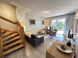 A modern living room with a staircase, a sofa, a coffee table, and a TV.