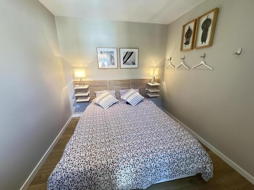 A bedroom with a bed, bedside tables, and wall-mounted lamps.