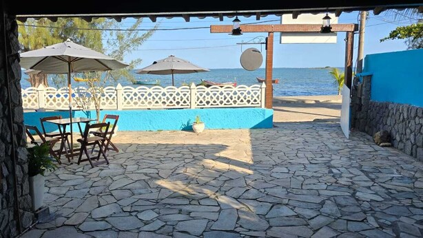 Un patio de piedra con mobiliario exterior, vistas al mar y una valla blanca.
