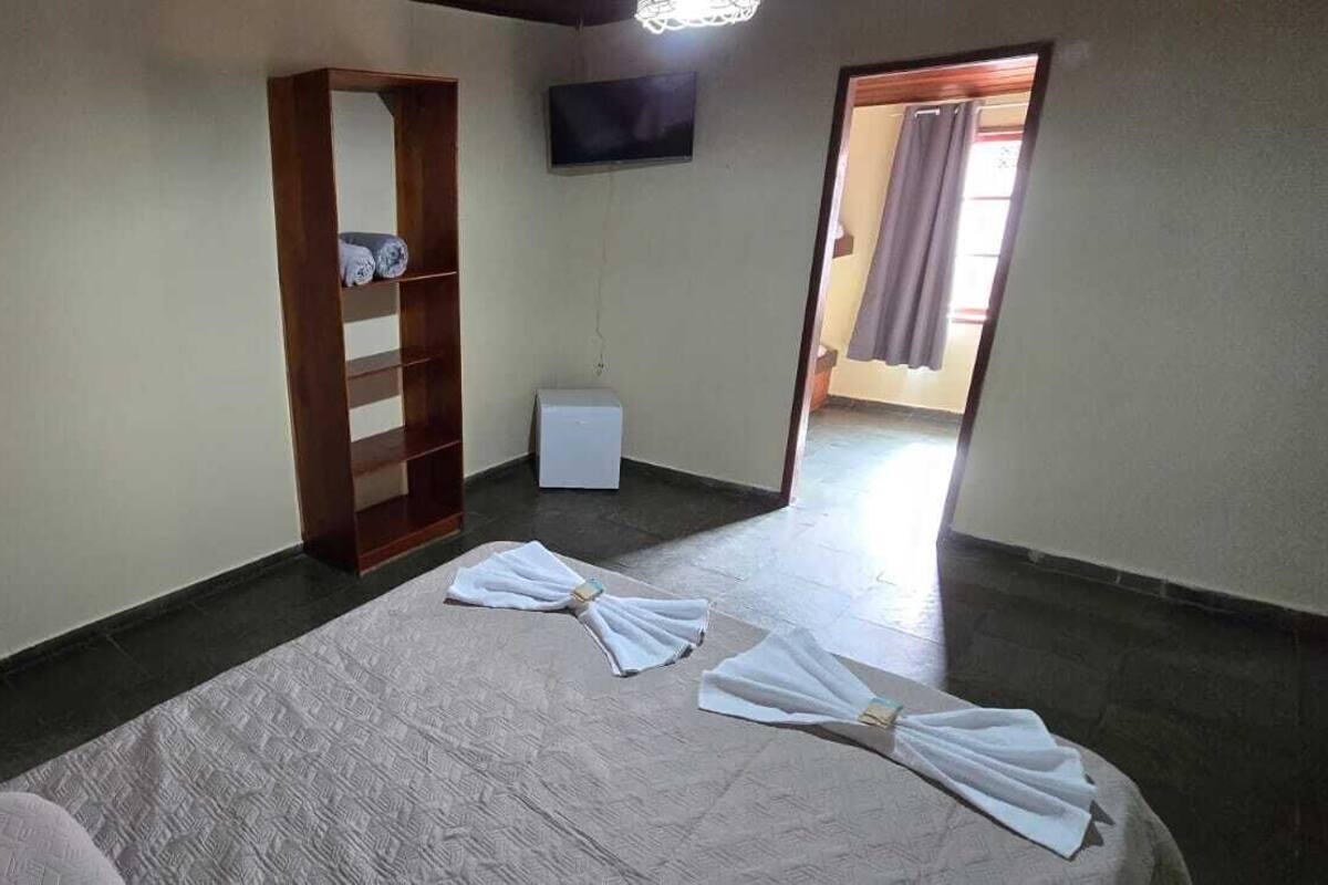 Una habitación de hotel con una cama, un armario, un televisor y una pequeña mesa.