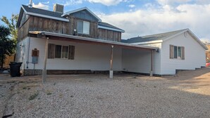 A two-story house with a covered patio and a gravel driveway.
