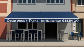 Ένα πολυώροφο κτίριο που στεγάζει ένα μπαρ και ένα εστιατόριο με την ονομασία «Desayunos y Tapas Bar Restaurante GELIN 2.0».