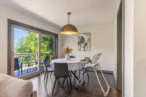 A dining area with a table, chairs, a vase of flowers, and a ceiling light. - 2 King Suites • Mountain Views • Near Rose Garden (Portland)