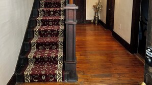 A wooden staircase with a red carpet leading to a door.