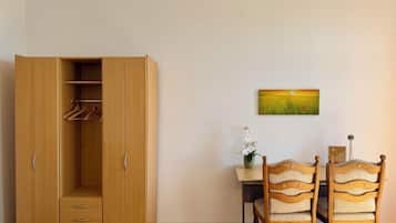 Ein Zimmer mit einem Holzschrank, einem Esstisch mit zwei Stühlen und einem Bild an der Wand.