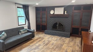 Una sala de estar con chimenea, un sofá, una mesa de centro y una ventana con cortinas.
