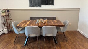 Un comedor con una mesa de madera, cuatro sillas grises y un tapiz abstracto blanco y negro.