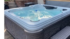 Un jacuzzi con revestimiento de piedra, un asiento incorporado y una pequeña mesa al lado.
