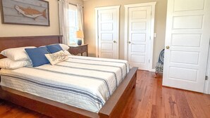 A bedroom with a wooden bed, a ceiling fan, and two white doors. - Scalloper`s Dream House (Port St. Joe)