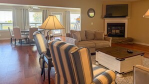 A living room with a sofa, chairs, a coffee table, a fireplace, and a TV mounted above it. - Scalloper`s Dream House (Port St. Joe)