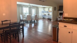 A spacious living area with a dining table, chairs, a kitchen counter, and a ceiling-mounted fish decoration. - Scalloper`s Dream House (Port St. Joe)