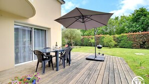 A patio with a table and chairs, a barbecue grill, and a large umbrella.