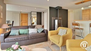 A modern living room with a leather sofa, a yellow armchair, and a dining area with a table and chairs.