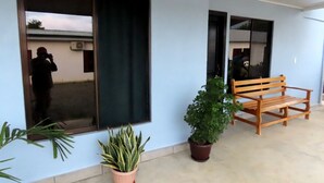 A building exterior with a large window, a wooden bench, and potted plants. - Villas Arena y Sol (Puerto Jiménez)
