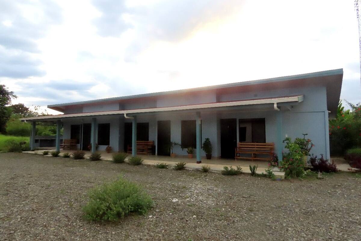 A two-story building with a covered porch and a gravel driveway.