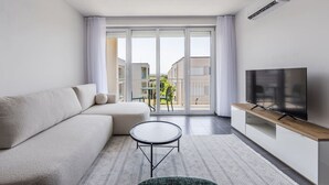 Uma sala de estar moderna com um sofá, uma mesa de centro e uma TV sobre um suporte de madeira.