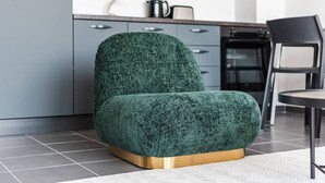 Cozinha moderna com armários cinza, uma cadeira preta e uma poltrona verde com base dourada.