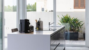 Una cocina moderna con cafetera, utensilios y una planta en maceta.