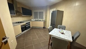 A compact kitchen with a dining area, including a table with chairs, a refrigerator, and a stove.