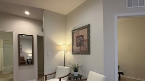 Ein Zimmer mit zwei Holzstühlen, einer Stehlampe und einem gerahmten Bild an der Wand.