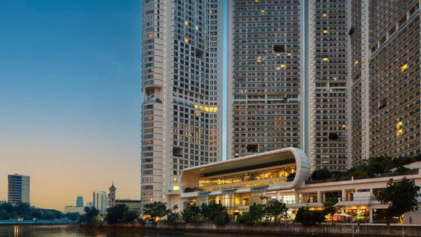 Un hôtel de grande hauteur, avec de nombreux étages, une façade en verre incurvée et une vue sur le front de mer.
