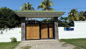 A gated entrance to a building with a tiled roof and a sign indicating it is the Hotel de Playa & Eventos.
