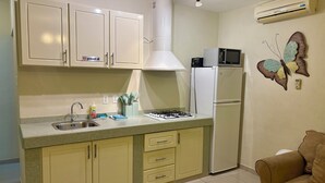 A kitchen with a gas stove, sink, cabinets, microwave, refrigerator, and a decorative butterfly wall piece. - Marvin's Apartment - 46 (Sint Michiel)