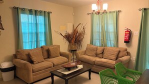 A living room with two beige sofas, a coffee table, a green chair, and a decorative vase with dried plants. - Marvin's Apartment - 46 (Sint Michiel)