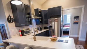 Una cocina moderna con una isla central, taburetes de bar, un ventilador de techo y un refrigerador.