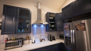 Una cocina moderna con armarios oscuros, una campana extractora de acero inoxidable, un tostador empotrado, una cafetera y un refrigerador con imanes.