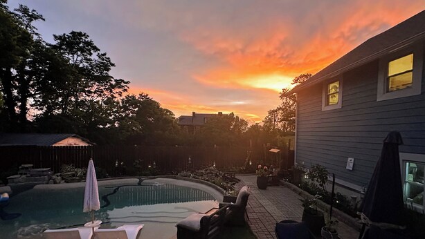 Un patio trasero con piscina, sillas de descanso y una zona de terraza.