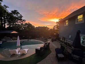 Un patio trasero con piscina, sillas de descanso y una zona de terraza.
