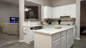 Una cocina moderna con armarios blancos, una isla grande y un horno empotrado.